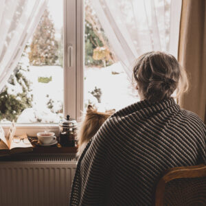 Elderly woman with dog looking out window